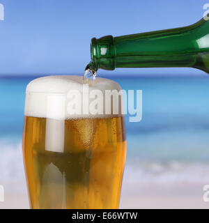 Verser la bière d'une bouteille dans un verre sur la plage et la mer Banque D'Images