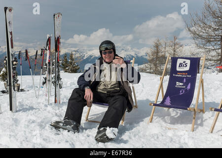 Détente et de skieur de boire du chocolat chaud assis dans une chaise longue à l'extérieur d'un restaurant de montagne dans la neige. Banque D'Images