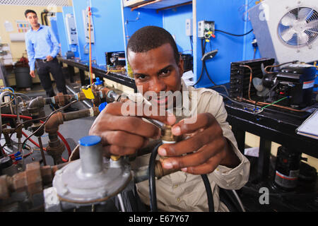 Student in wheelchair examinant les distributeurs de carburant sur le mazout de chauffage, ventilation et climatisation en classe Banque D'Images