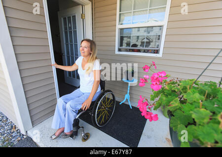 Femme avec de la moelle épinière en fauteuil roulant qui sort de sa maison Banque D'Images