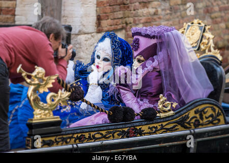 Deux femmes dans des costumes bleus et violets photographiée sur une gondole à Venise pendant le carnaval. Banque D'Images