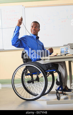 Une étudiante en génie dans un fauteuil roulant la préparation de laboratoire pour expérimenter avec l'oscilloscope et prototypage électronique breadboard Banque D'Images