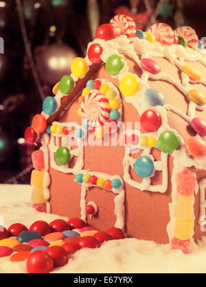 Belle table de Noël en face de l'arbre de Noël, avec une maison en pain d'épices faits avec du glaçage et des bonbons bonbons, Banque D'Images