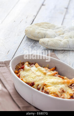 Les frites avec du chili au gratin dans une caserole sur un tableau blanc rustique Banque D'Images