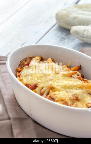 Les frites avec du chili au gratin dans une caserole sur un tableau blanc rustique Banque D'Images