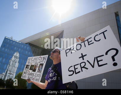 Los Angeles, Californie, USA. 17 août, 2014. Un jeune homme détient deux pancartes jusqu'en face de l'Administration centrale avec la réflexion LAPD de Los Angeles City Hall sur la façade en verre à l'arrière-plan.----environ 800 manifestants se sont réunis devant le Département de la police de Los Angeles dans le centre-ville le dimanche après-midi pour protester contre l'agent en cause d'un tournage Ford Ezell dans le centre-sud de Los Angeles la semaine dernière ainsi que d'appuyer les résidents de Ferguson, Missouri, dans leurs manifestations contre la police. La foule assemblée affichent des pancartes et signe avec des slogans contre la police Banque D'Images