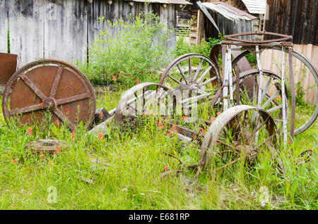 Vieilles machines rouillées de l'équipement agricole roue pour wagon historique de la vieille ville de la ruée vers l'Barkerville, l'intérieur de la Colombie-Britannique, BC, Canada. Banque D'Images