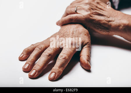 Macro de vieille femme main sur une surface grise. Se concentrer sur les doigts des personnes de sexe féminin. Banque D'Images