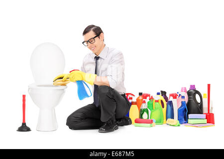 Homme assis par un tas de toilettes avec produits de nettoyage derrière lui Banque D'Images