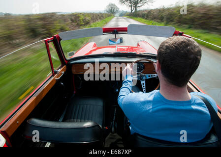 Au volant d'une Triumph Herald convertible voiture classique rapidement sur un pays B road Banque D'Images