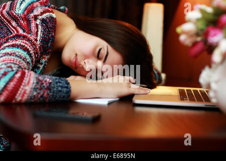 Tired woman dormir sur la table à la maison Banque D'Images