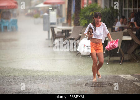 Woman carrying shopping piégés par la tempête tropicale Miami Banque D'Images