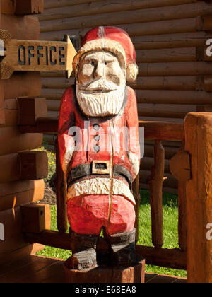 Père Noël en bois figure sur le porche d'une cabane de fabrication Banque D'Images