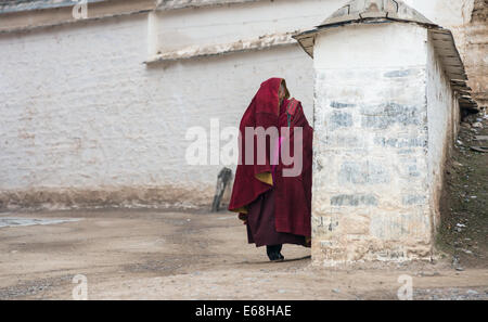 Les personnes âgées moine tibétain de Labrang monastère se cache à partir d'une foule de photographes de la Chine derrière le mur Banque D'Images