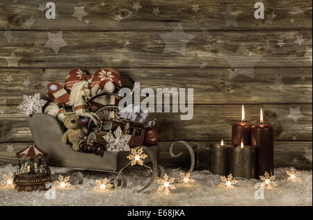 Vieux jouets d'enfants et quatre bougies de l'avent en feu rouge sur fond vintage en bois pour la décoration. Banque D'Images