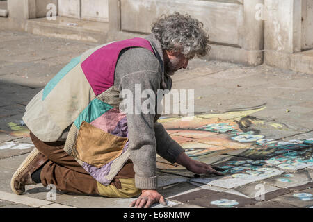 Un artiste de la rue de sexe masculin ne trottoirs colorés dessins pendant le carnaval sur une rue piétonne principale de Venise. Banque D'Images