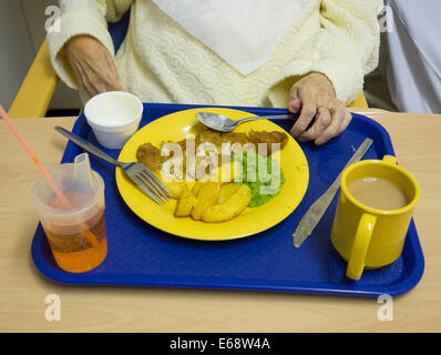 Hospital de la nourriture. Une femme de 90 ans la consommation de poisson et frites à l'hôpital du NHS en Angleterre, Royaume-Uni Banque D'Images