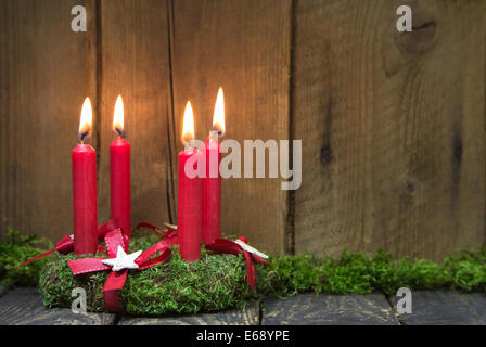 L'Avent ou couronne de Noël avec quatre bougies en cire rouge sur fond de bois. Banque D'Images