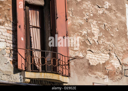 Fenêtre avec volets sur la vieille maison en brique avec pealing plaster à Venise. Banque D'Images