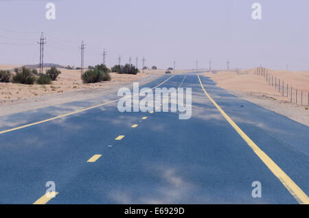 Le sable qui balaye la route à travers le désert, Dubaï, Emirats Arabes Unis EMIRATS ARABES UNIS. Banque D'Images