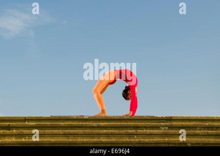 Jeune femme la pratique de l'Hatha Yoga, à l'extérieur, montrant la pose Chakrasana, Urdhva Dhanurasana, poser des roues Banque D'Images