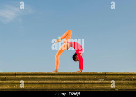 Jeune femme la pratique de l'Hatha Yoga, à l'extérieur, montrant la pose Chakrasana, Urdhva Dhanurasana, poser des roues Banque D'Images