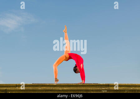 Jeune femme la pratique de l'Hatha Yoga, à l'extérieur, montrant la pose Chakrasana, Urdhva Dhanurasana, poser des roues Banque D'Images