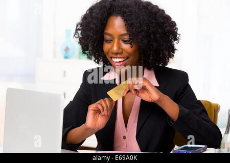 Mixed Race woman shopping on laptop at desk Banque D'Images