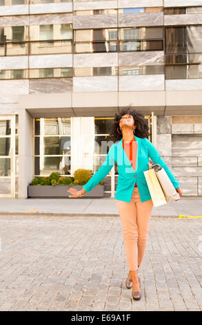 Mixed Race woman carrying shopping bags on city street Banque D'Images