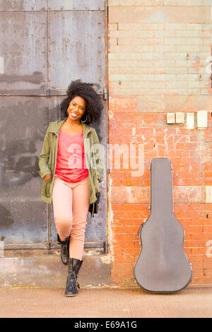 Mixed Race woman avec étui à guitare sur le trottoir de la ville Banque D'Images