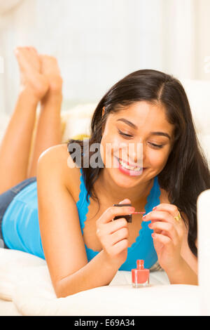 Hispanic woman painting her nails sur canapé Banque D'Images