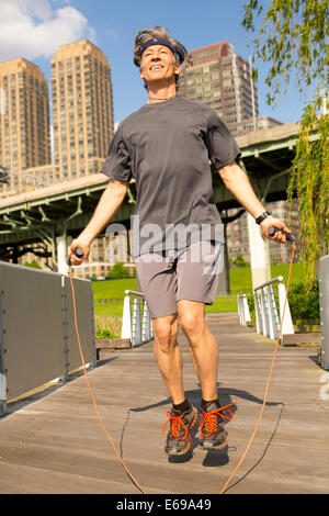 Caucasian man jumping rope in urban park Banque D'Images