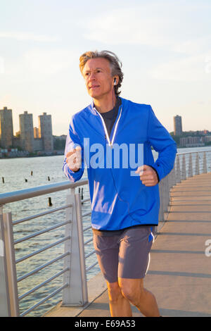 Caucasian man jogging on urban waterfront Banque D'Images