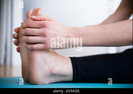 Caucasian woman stretching jambes on yoga mat Banque D'Images