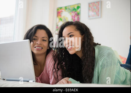 Mère et fille using laptop on bed Banque D'Images