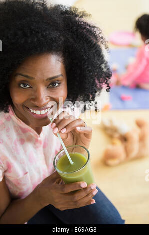 Smiling woman drinking jus vert Banque D'Images