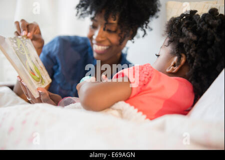 Mère et fille lire au lit Banque D'Images