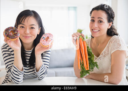 Les femmes qui choisissent entre les beignets et les carottes Banque D'Images