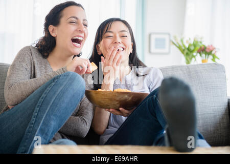 Les femmes rire sur canapé ensemble Banque D'Images