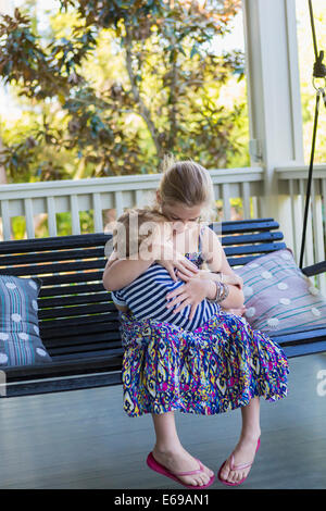 Caucasian girl holding frère le porche swing Banque D'Images