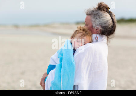 Caucasian woman exerçant son petit-fils sur la plage Banque D'Images