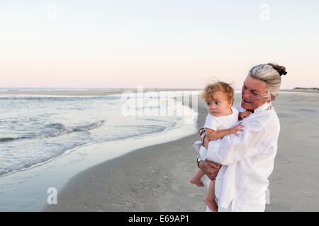 Caucasian woman exerçant son petit-fils sur la plage Banque D'Images