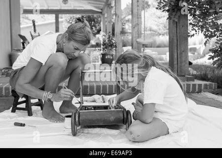 Caucasian mother and daughter painting toy on porch Banque D'Images