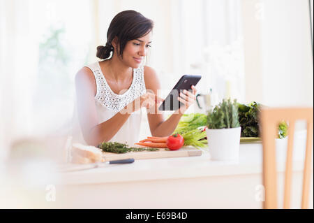 Hispanic woman cooking with digital tablet Banque D'Images