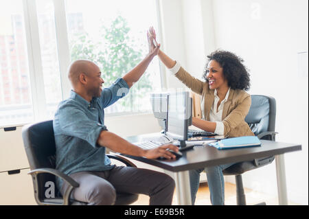 Les gens d'affaires high fiving in office Banque D'Images