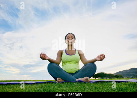 Pregnant woman meditating in park Banque D'Images