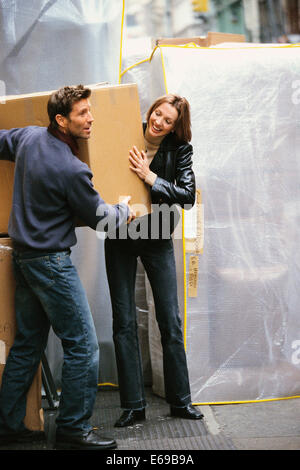 Couple carrying boxes on city street Banque D'Images