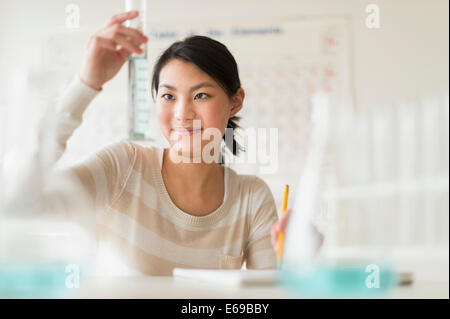 Mixed Race teenage girl doing experiment in science lab Banque D'Images