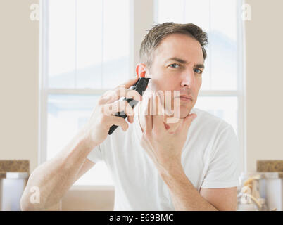 Caucasian man shaving in bathroom Banque D'Images
