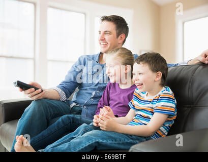 Père de race blanche et les enfants à regarder la télévision sur le canapé Banque D'Images